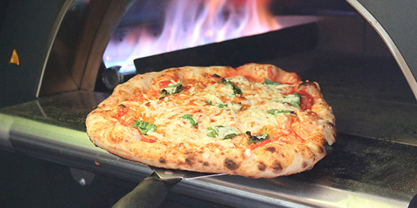 Vegan margherita pizza coming out of the oven